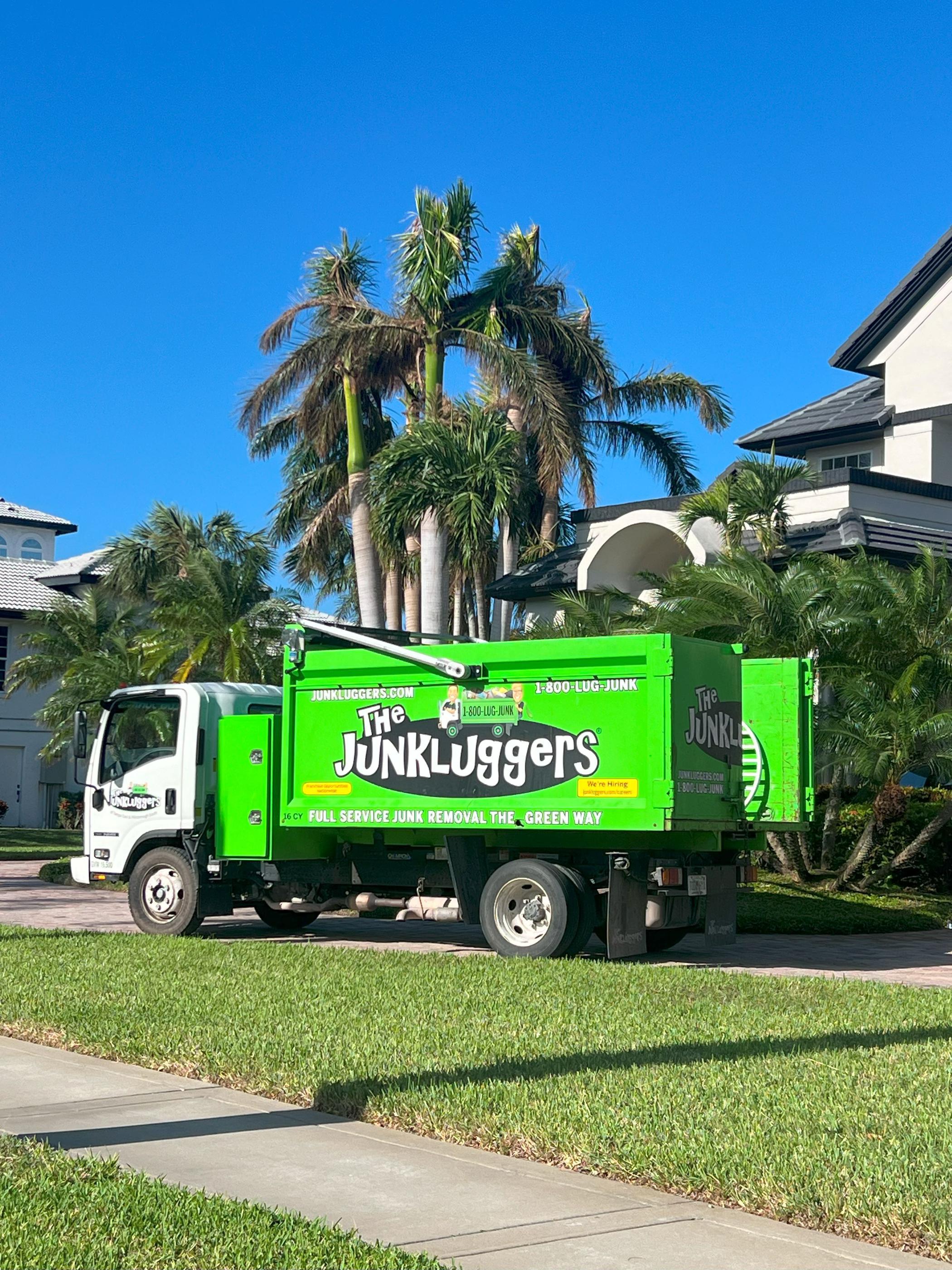 Our green Junkluggers truck parked by palm trees in front of a home