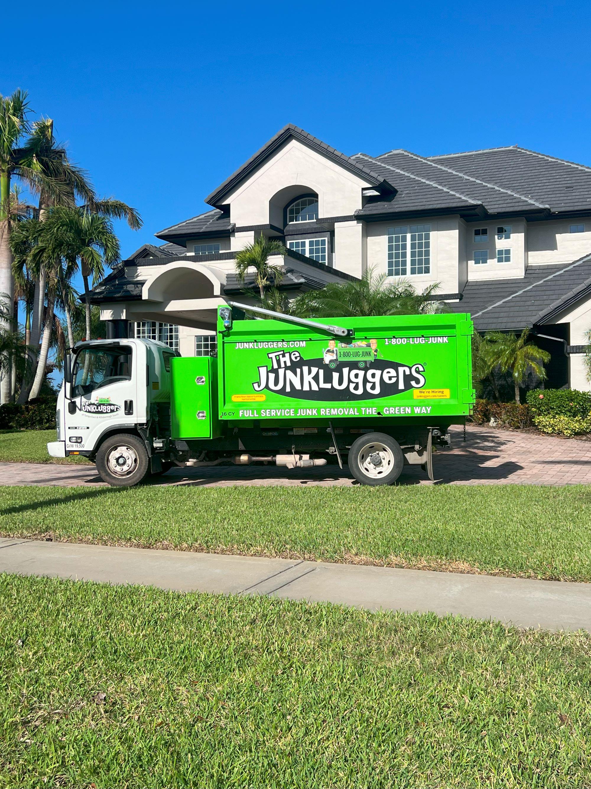 Junkluggers truck parked in front of a large home