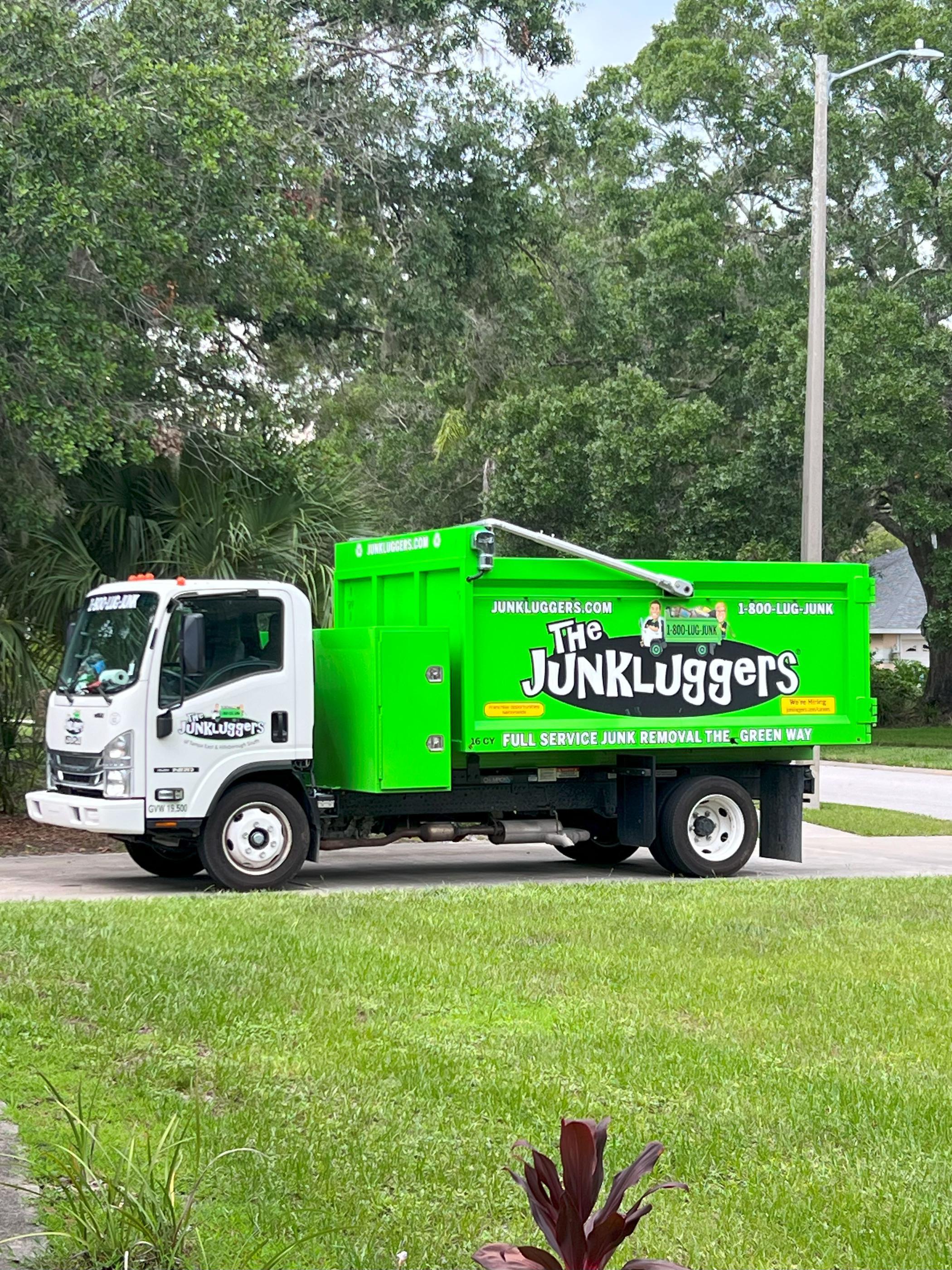 Our green Junkluggers truck parked in a neighborhood