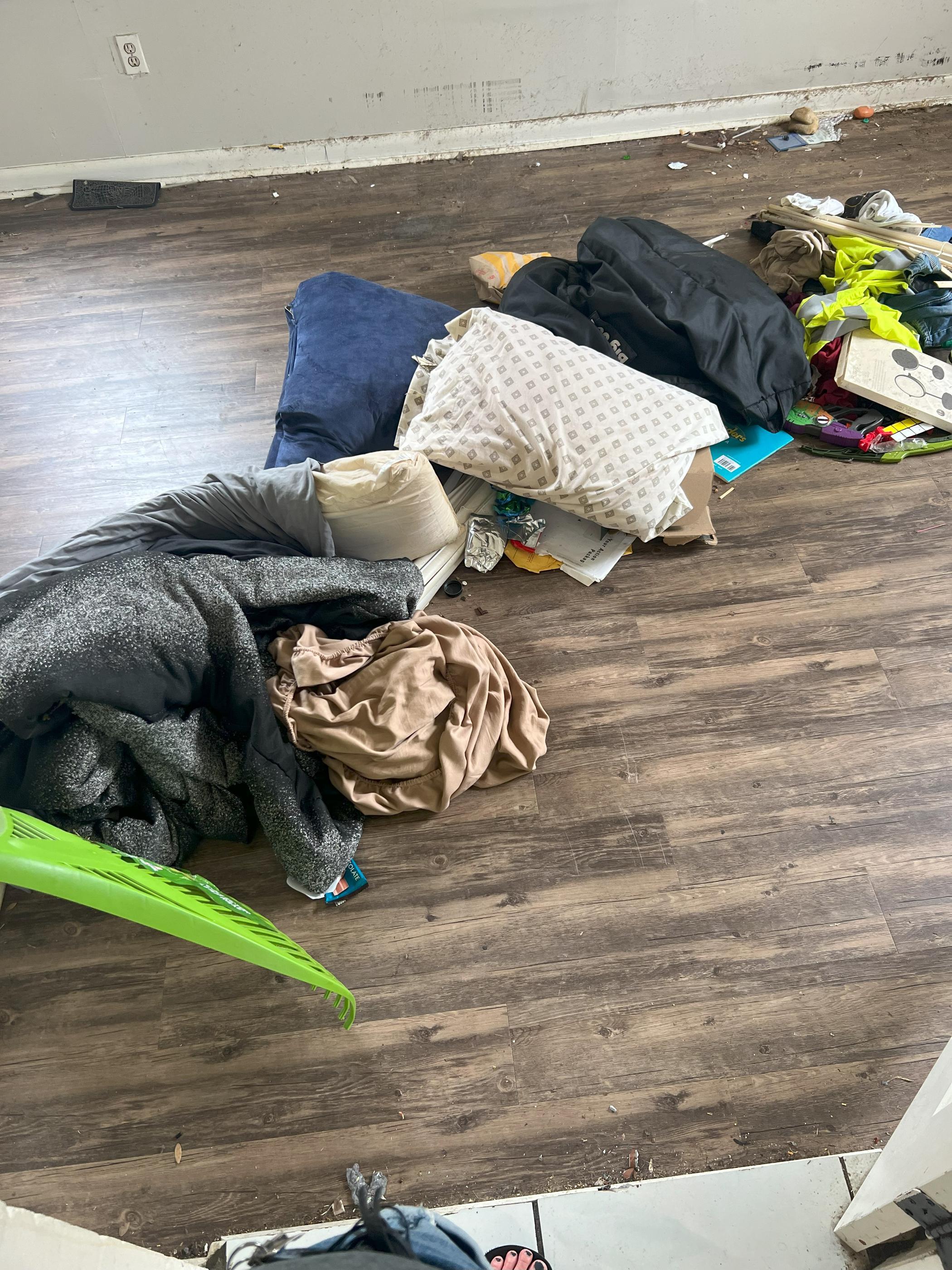 Scattered textiles, including blankets, pillows, and clothing on the floor