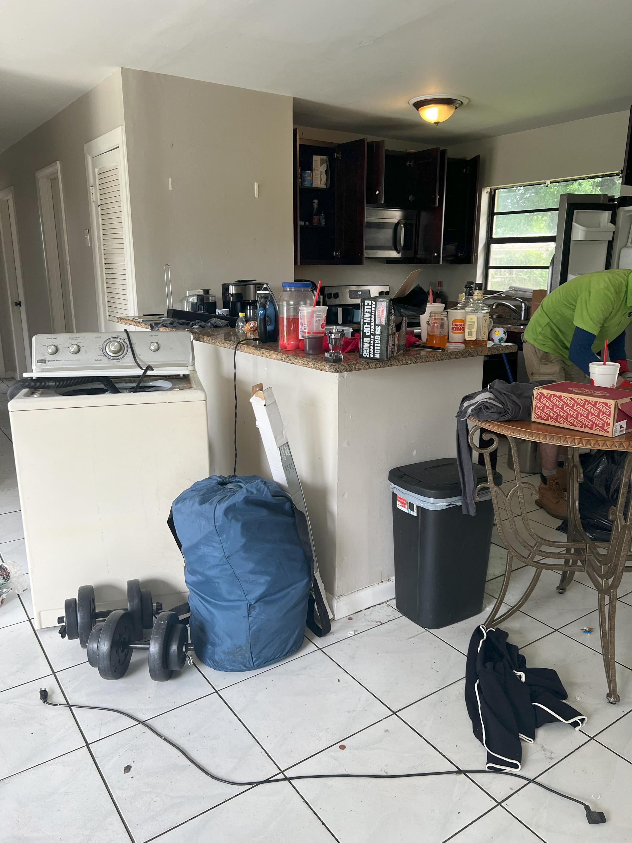 A kitchen filled with broken appliances, old electronics, and other household items