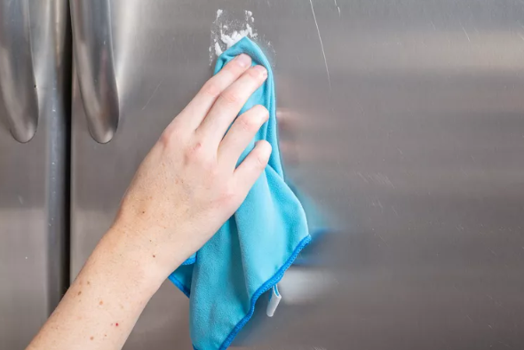 hand scrubbing fridge with blue cloth