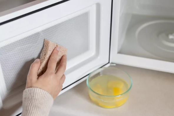 hand scrubbing inside of microwave with sponge