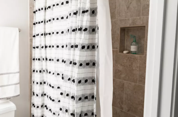 shower with white shower curtain with black spots