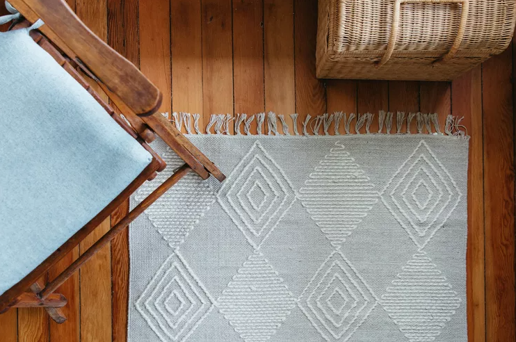 birds eye view of floor with rug, rocking chair and whicker basket in frame