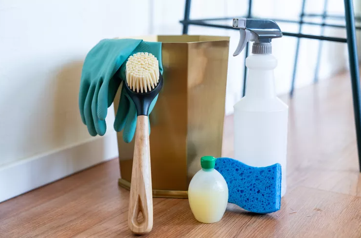 scrub brush leaning up against bin with sponge next to it