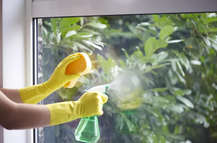 hands in yellow gloves cleaning window