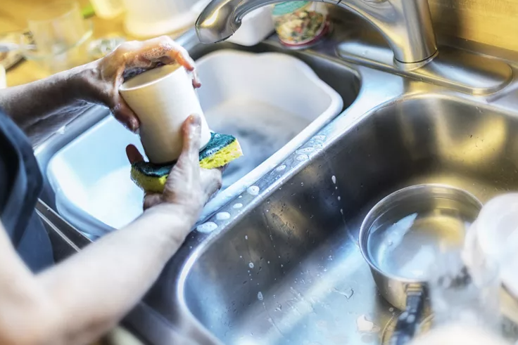 person scrubbing mug with sponge
